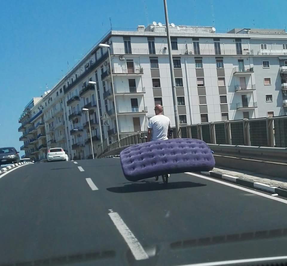 Bari, ponte di via di Vagno foto choc, uomo in bici trasporta un enorme materasso blu, la foto diventa virale