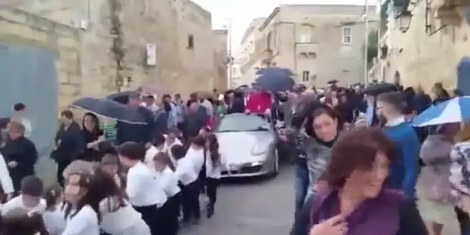Nomina ad arciprete, il prete per festeggiare sfila in  paese a bordo si una sua Porsche argentata, trainata da 50 bambini