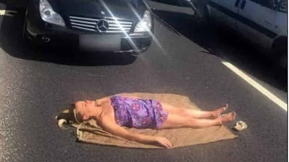 Strada verso il mare bloccata per ore da un incidente, una donna non si scoraggia, stende l’asciugamano e prende il sole stesa sull’asfalto rovente