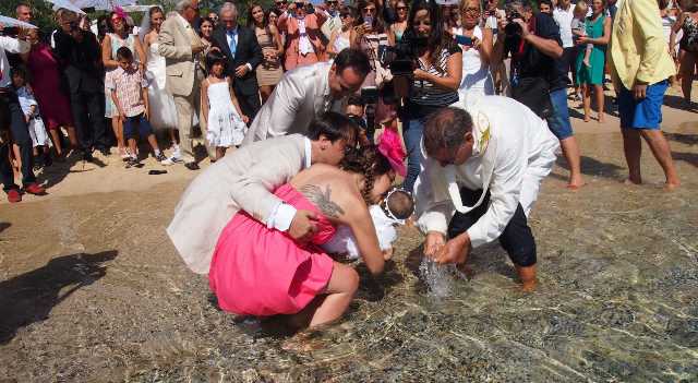 Coppia decide di celebrare il battesimo del figlio in modo originale in riva al mare ma un’onda uccide chierichetto