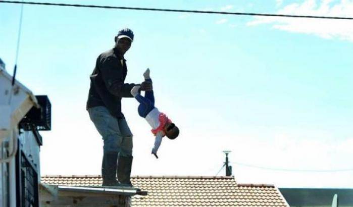 Sale sul tetto di una casa per protesta e fa dondolare nel vuoto la sua bambina, poi la lancia